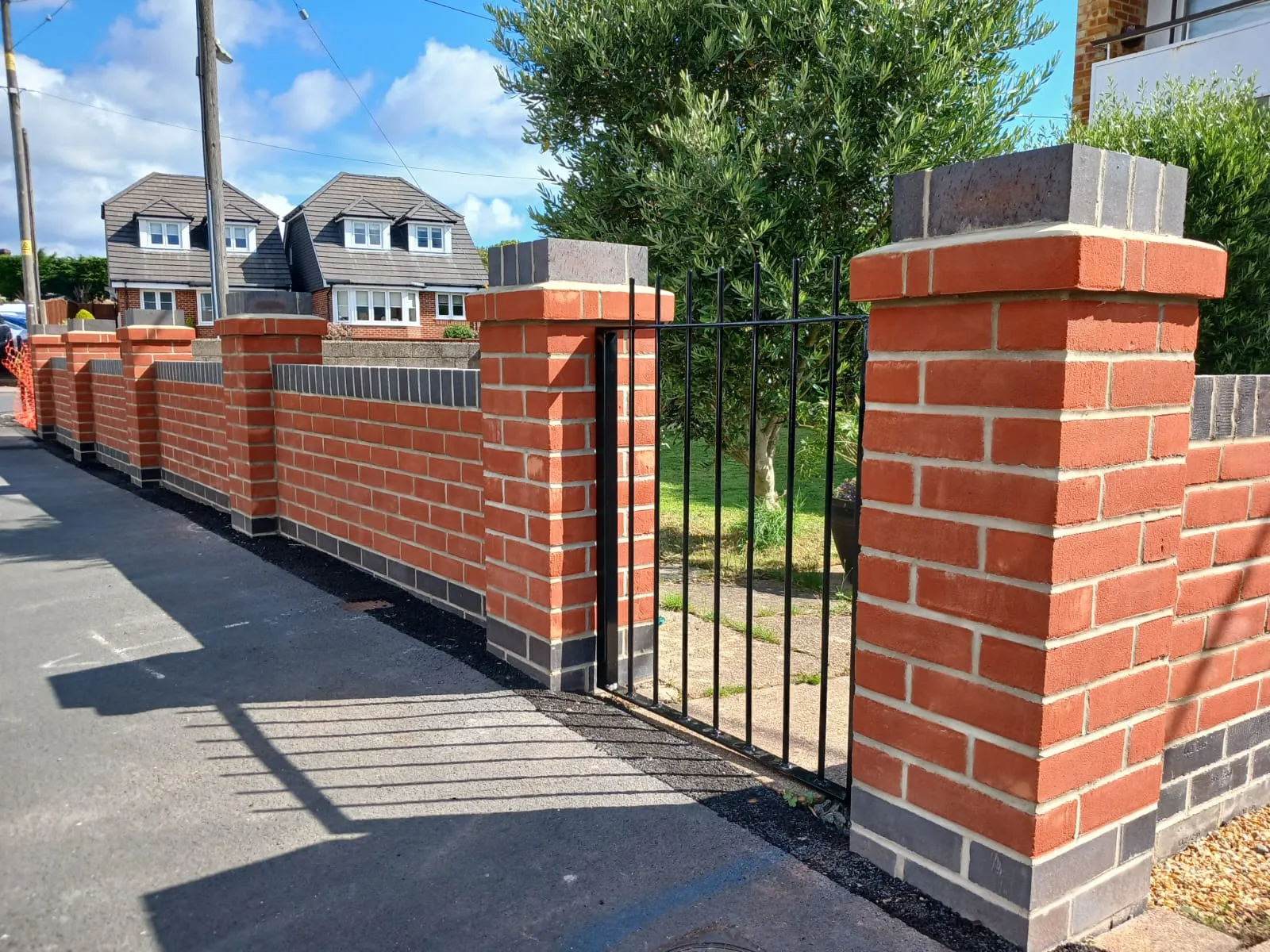 A red brick fence with a black gate.