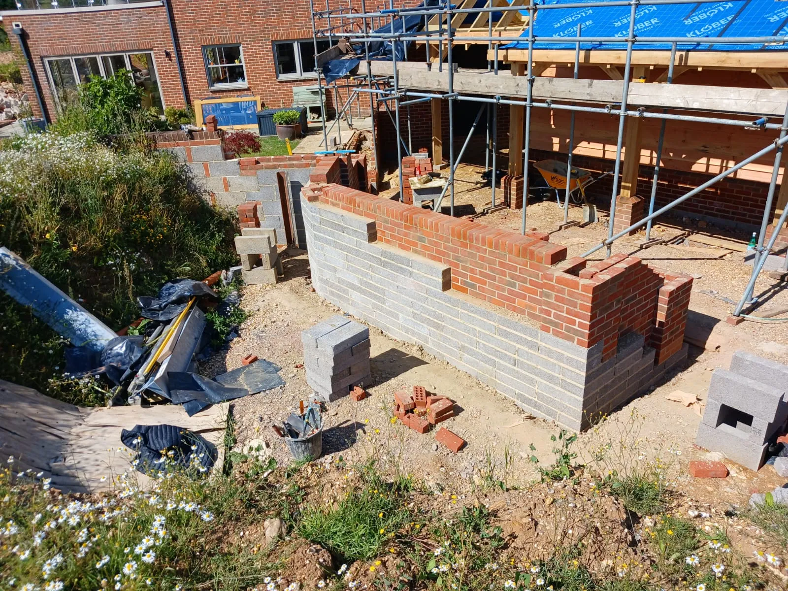 A brick house under construction with a blue tarp.