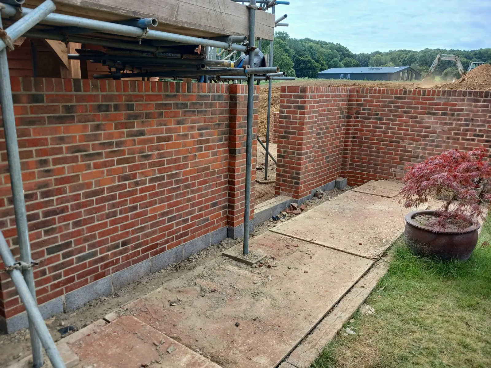 A brick wall with a metal pipe and a potted plant.
