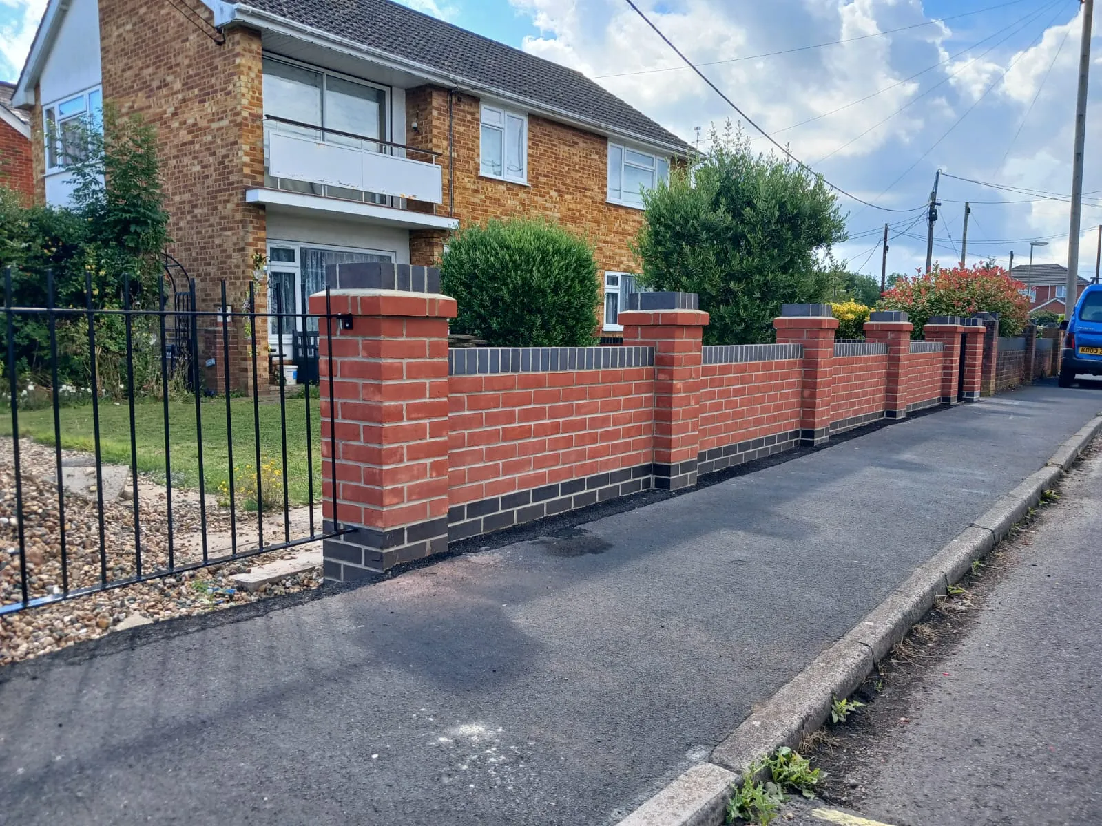 A red brick fence next to a brick house.