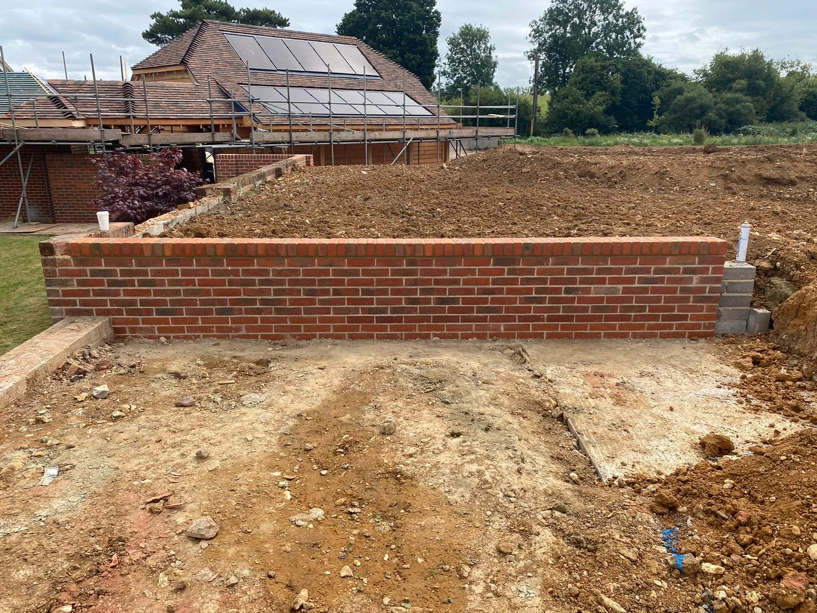 A brick wall is being built in front of a house.